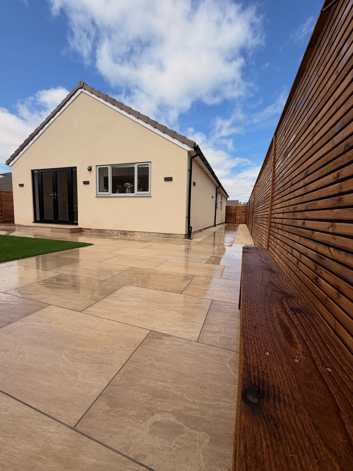 Aged Raj Green porcelain paving continuing from the rear patio along the side of the house in Gomersal
