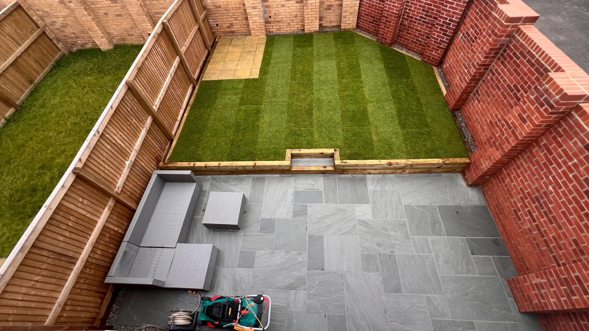 Aerial view of a completed porcelain patio, lawn and raised garden layout