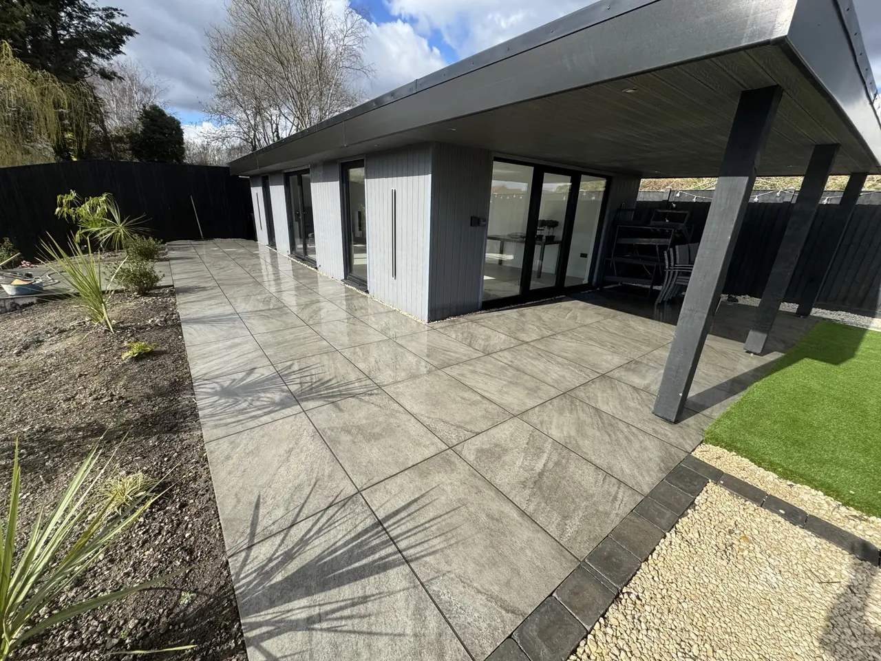 Completed porcelain terrace wrapping around a modern garden room